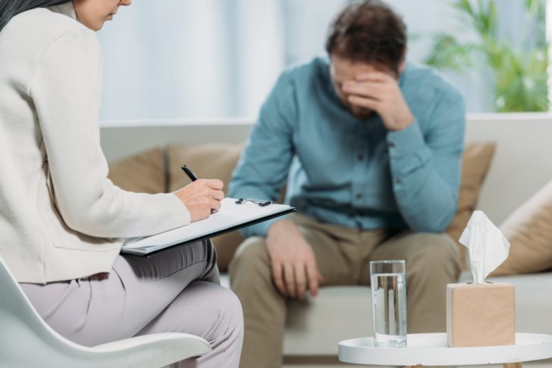 A man sitting on a couch talking to a counselor during his individual therapy session